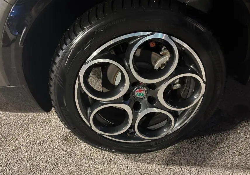 Gros plan sur la jante alliage 18 pouces noire et argentée de l'Alfa Romeo Tonale gris, avec logo central visible.