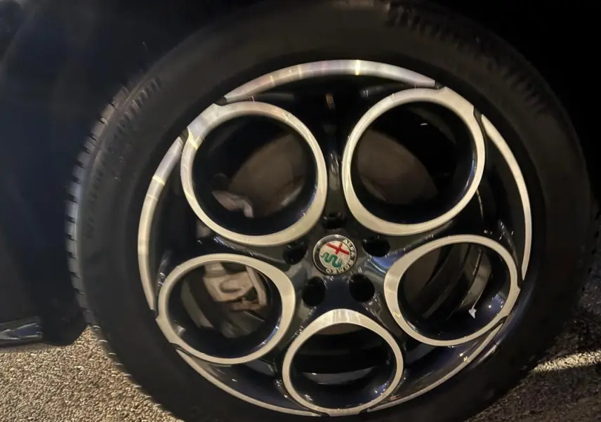 Gros plan sur la jante alliage 18 pouces noire et argentée de l'Alfa Romeo Tonale gris, avec logo au centre.