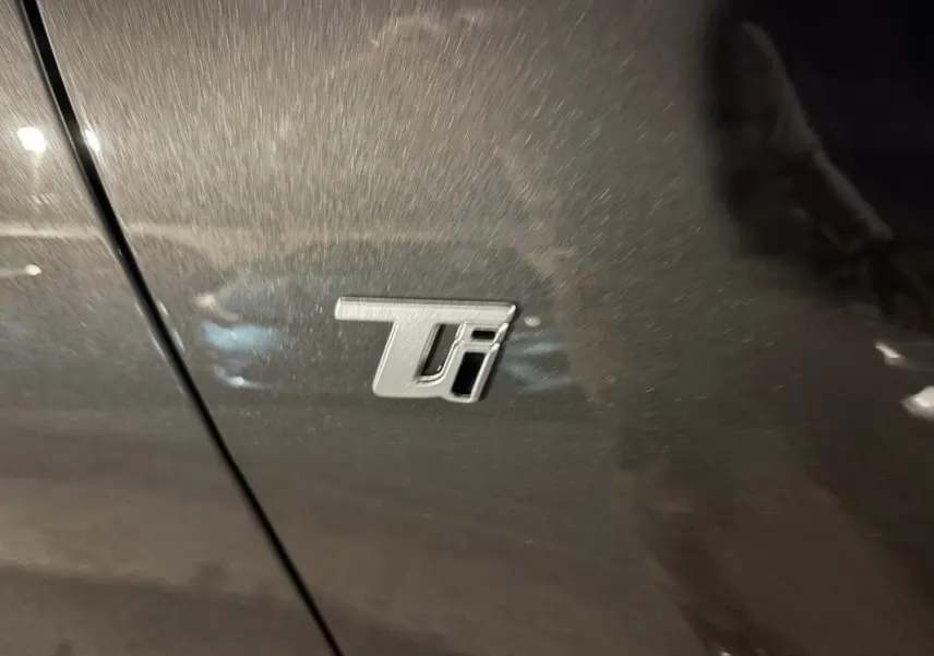 Gros plan sur l’écusson Ti argenté sur la porte grise métallisée de l’Alfa Romeo Tonale 2023.