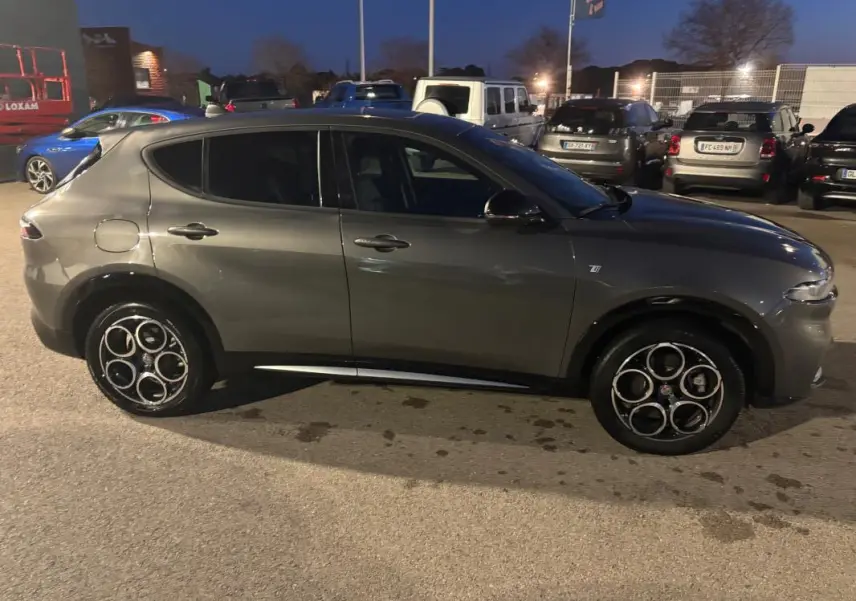 Vue de profil côté gauche d'une Alfa Romeo Tonale gris métallisé avec jantes alliage distinctives en cercle.