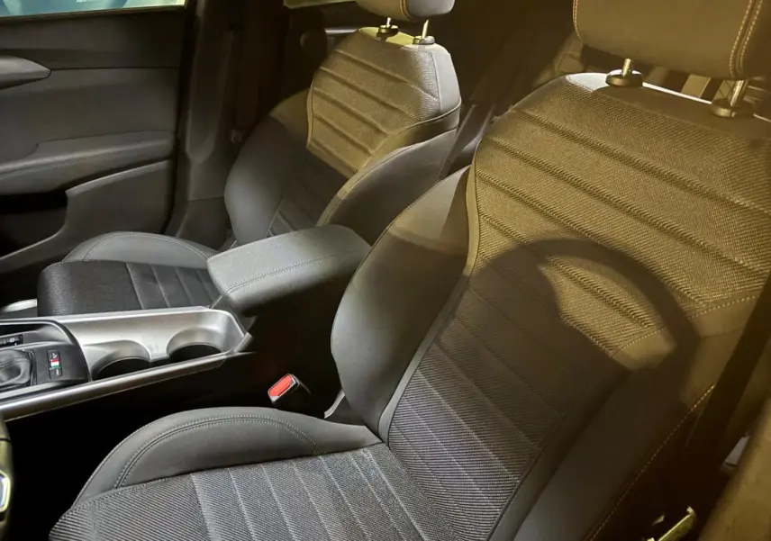 Vue intérieure rapprochée des sièges avant sport noirs de l'Alfa Romeo Tonale 2023, avec accoudoir central et console.