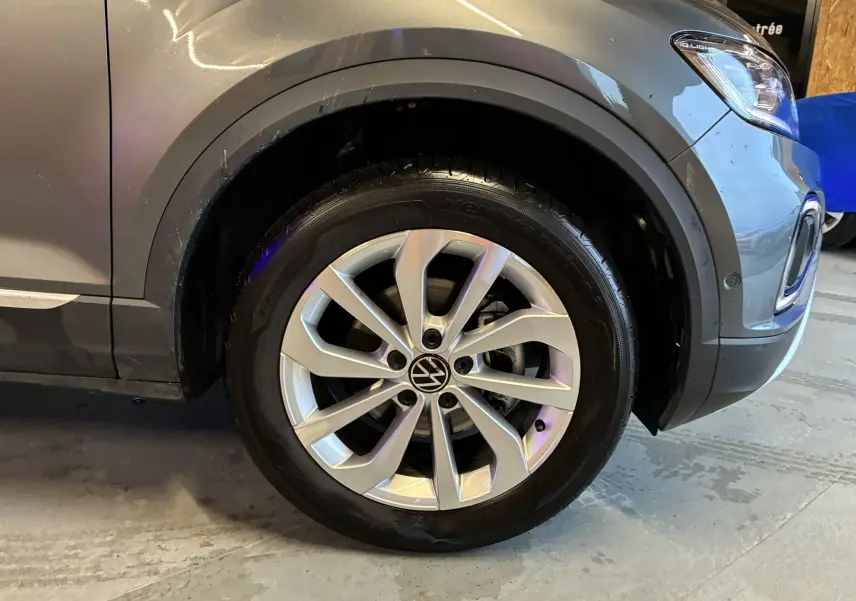 Gros plan sur la roue avant droite d’un Volkswagen T-Roc gris 2023, mettant en valeur la jante alliage et le passage de roue.