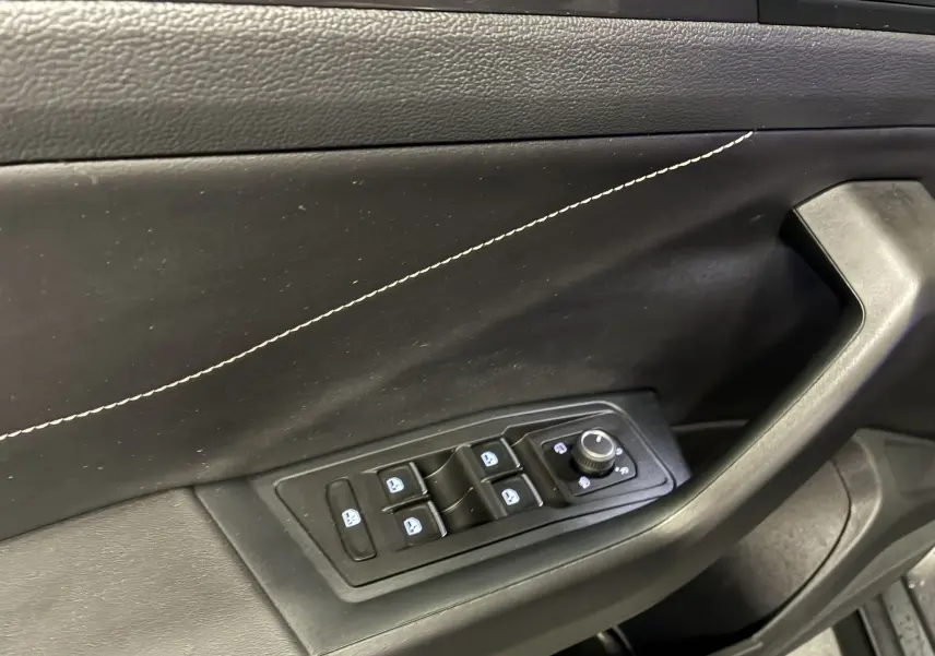 Détail de la porte intérieure côté conducteur du Volkswagen T-Roc gris, avec commandes électriques des vitres et réglage des rétroviseurs.