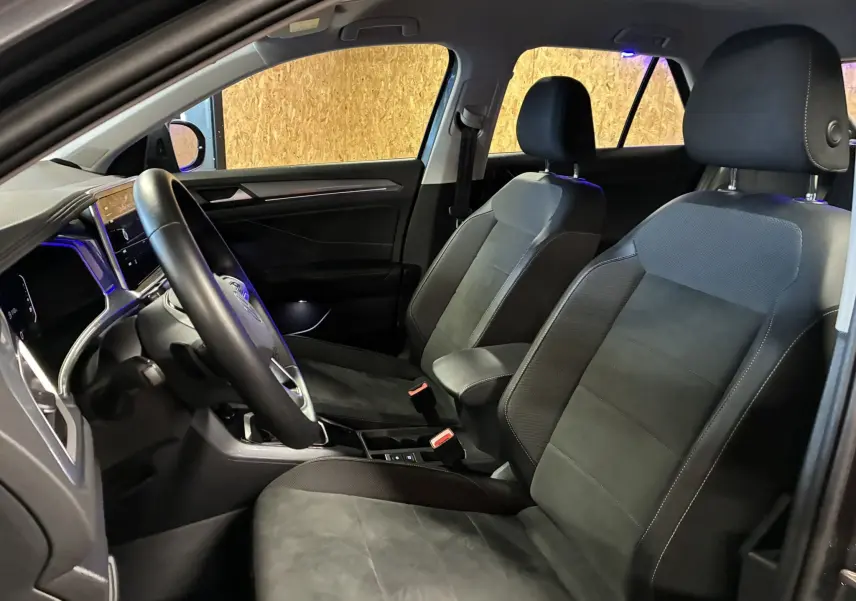 Vue intérieure côté conducteur du Volkswagen T-Roc 2023 avec sièges tissu noir et tableau de bord moderne.