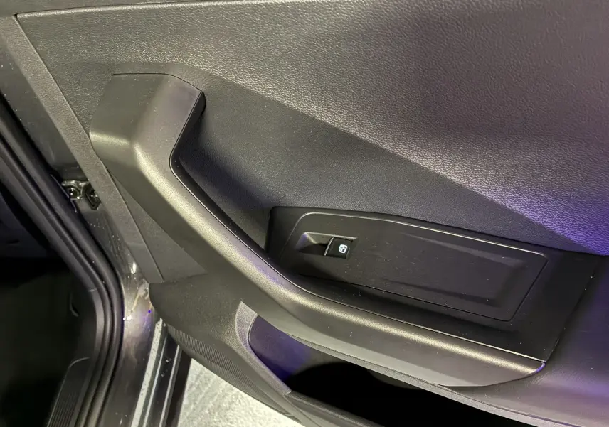 Détail de la poignée intérieure côté gauche de la porte avant grise du Volkswagen T-Roc 2023 avec bouton de commande de vitre.