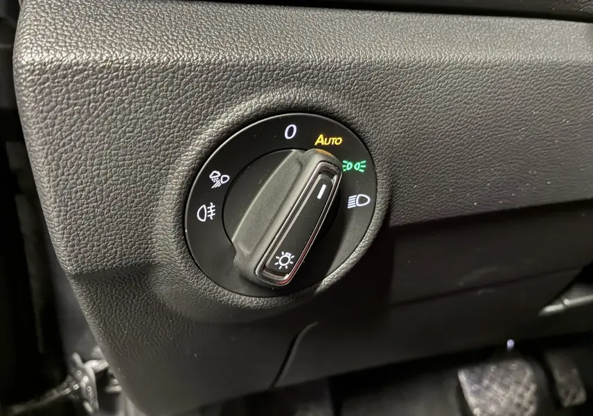 Gros plan sur le bouton de commande des phares du Volkswagen T-Roc gris, avec fonction automatique activée.