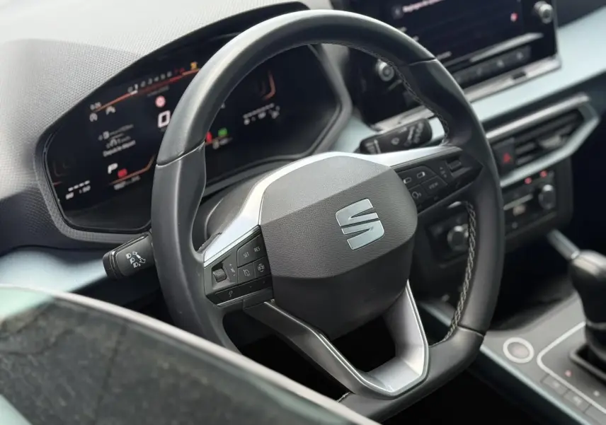Vue rapprochée du volant noir de la SEAT Arona 2025 avec tableau de bord digital et console centrale visible.