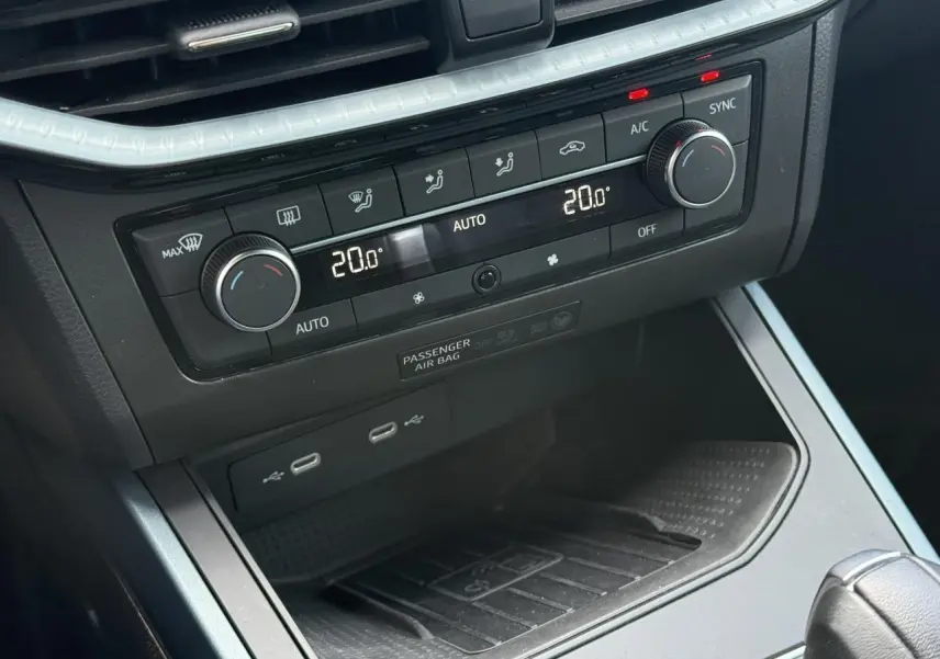Vue rapprochée de la console centrale du SEAT Arona gris, montrant la climatisation automatique bi-zone et les ports USB.
