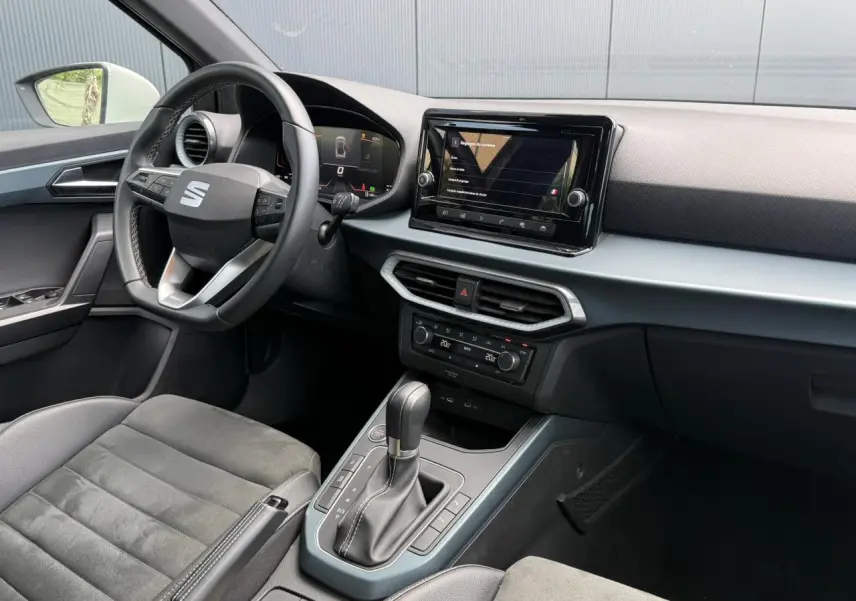 Vue intérieure côté conducteur du SEAT Arona gris Cliff 2025, avec tableau de bord digital et console centrale moderne.