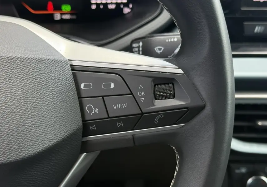Gros plan sur la partie droite du volant noir du SEAT Arona 2025 avec commandes multifonctions et combiné digital en arrière-plan.