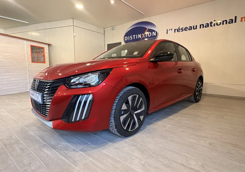 Peugeot 208 Active rouge vue 3/4 avant droit en intérieur, avec calandre noire et feux LED distinctifs.