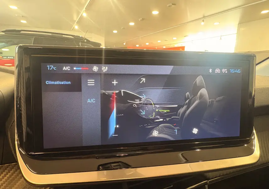 Écran tactile central affichant le réglage de la climatisation dans une Peugeot 208 rouge, vue intérieure.