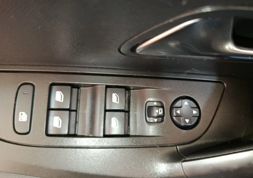 Gros plan sur les commandes de lève-vitres et réglage des rétroviseurs côté conducteur d'une Peugeot 2008 bleu 2021.