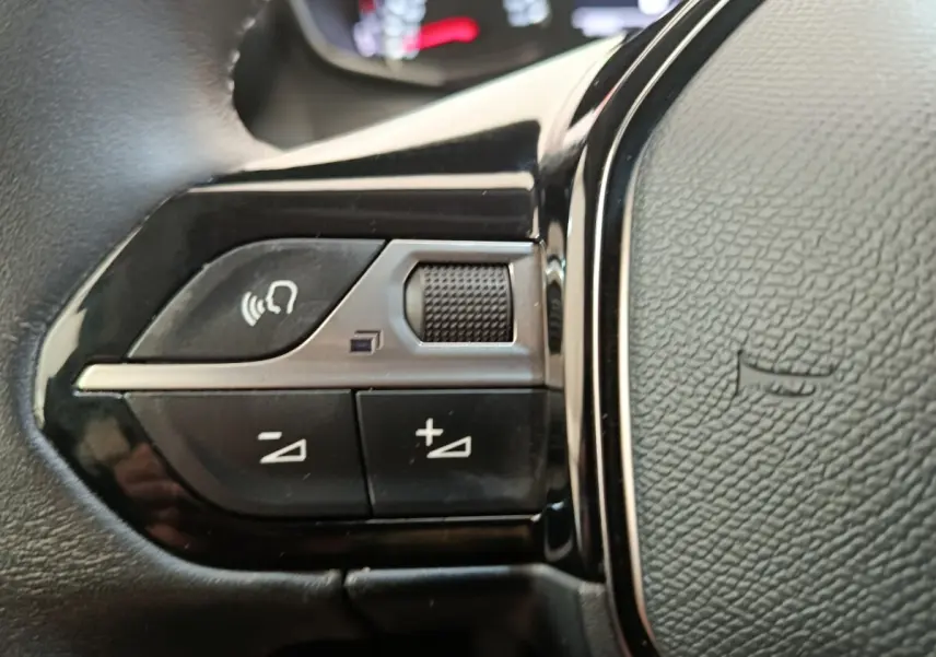 Gros plan sur les commandes multifonctions du volant cuir noir du Peugeot 2008 PureTech 100 S&S Allure Pack.