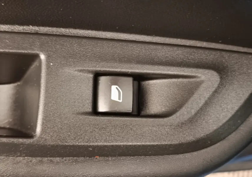 Bouton de commande de lève-vitre électrique noir sur panneau intérieur d'une Peugeot 2008 PureTech bleu, vue rapprochée.