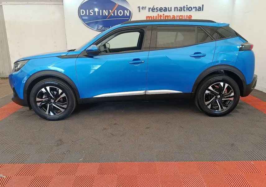 Vue de profil côté gauche d’un Peugeot 2008 bleu 2021 avec jantes alliage noires et toit noir contrasté.