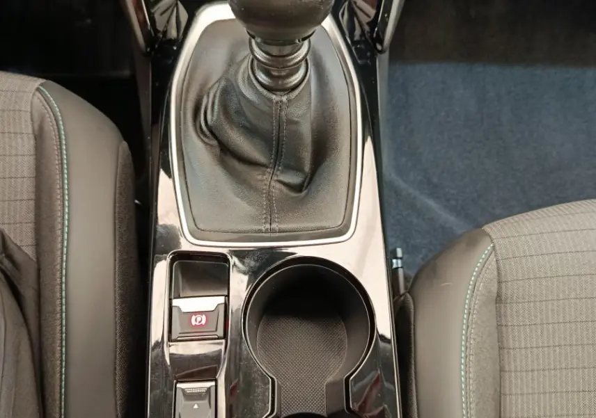 Vue intérieure centrée sur la console centrale noire avec levier de vitesses manuel et porte-gobelets du Peugeot 2008 bleu.