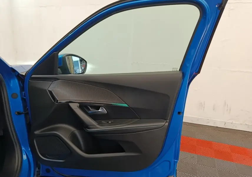 Vue intérieure de la porte avant gauche bleu vif d'une Peugeot 2008 avec garniture noire et insert décoratif texturé.