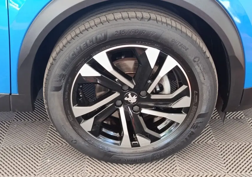Gros plan sur la roue avant droite noire et argentée du Peugeot 2008 bleu, mettant en valeur la jante au design moderne.