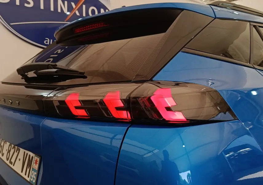 Vue 3/4 arrière du Peugeot 2008 bleu avec feux arrière LED en forme de griffes rouges distinctives.