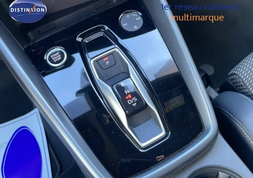 Gros plan sur la console centrale noire brillante de l'Audi A3 Sportback 2025 avec levier de vitesses automatique et bouton start/stop.