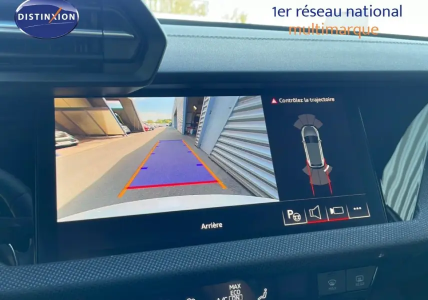 Écran de caméra de recul intérieur d’Audi A3 Sportback blanc Ibis, affichant les lignes de guidage et l’environnement arrière.