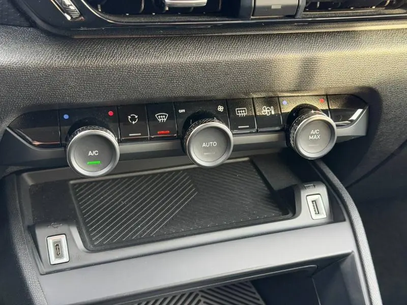 Gros plan sur la console centrale du Citroën C4 X 2025, montrant les commandes de climatisation avec finitions noires.