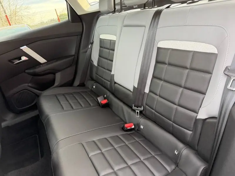 Vue intérieure des sièges arrière en cuir noir et gris clair de la Citroën C4 X 2025, avec ceintures de sécurité visibles.