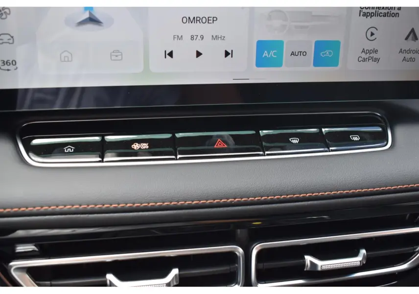 Gros plan sur la console centrale du MG Motor EHS gris 2026, avec boutons de climatisation et finition cuir avec surpiqûres orange.