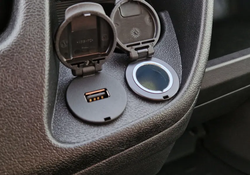 Gros plan sur la prise USB et l'allume-cigare ouverts dans l'habitacle noir du Citroën Jumper blanc 2023.