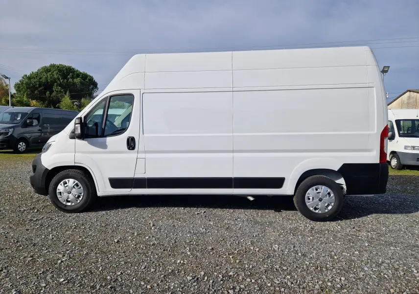 Vue de profil côté gauche d'un utilitaire blanc Citroën Jumper L3H3 2023 avec toit surélevé sur un sol gravillonné.