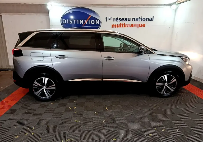 Profil droit d'un Peugeot 5008 gris clair 2020, SUV familial avec toit chromé et jantes alliage modernes.