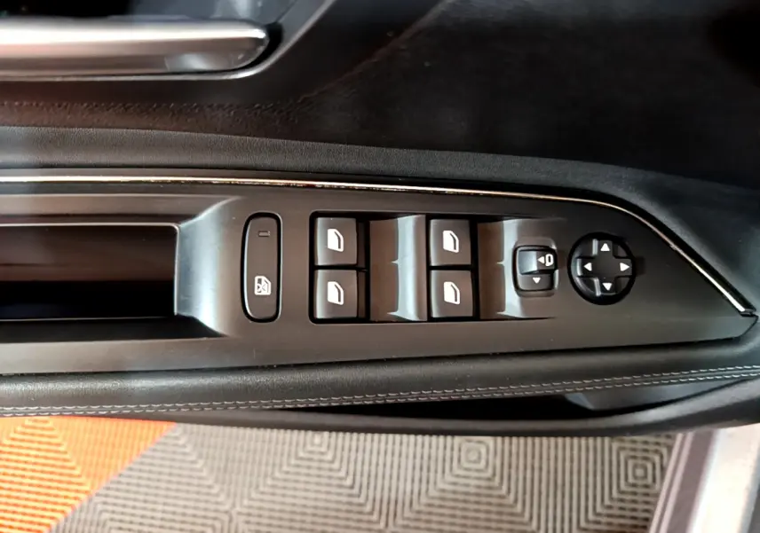 Vue rapprochée des commandes de lève-vitres et rétroviseurs sur la porte côté conducteur d'un Peugeot 5008 gris clair 2020.
