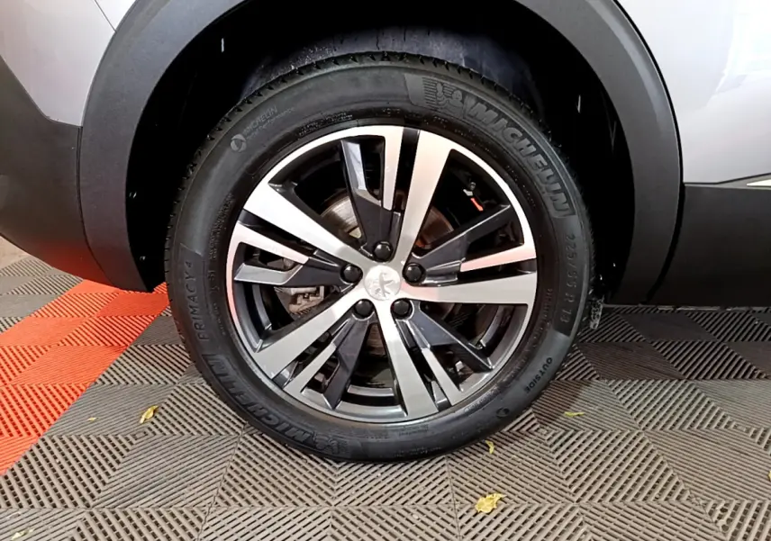 Gros plan sur la roue avant droite du Peugeot 5008 gris clair, soulignant la jante alliage bicolore et le pneu Michelin.