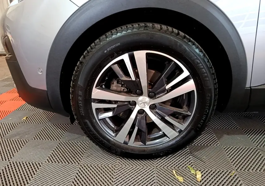 Gros plan sur la roue avant gauche gris clair du Peugeot 5008 avec jante alliage et logo lion central.