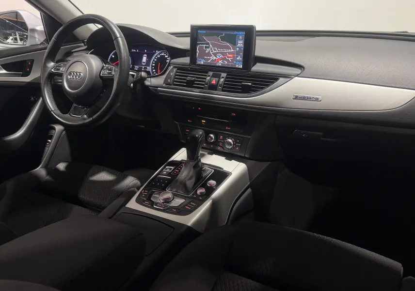 Intérieur de l'Audi A6 Avant 2015, vue côté conducteur, tableau de bord avec écran GPS et console centrale en aluminium.