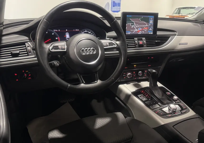 Vue intérieure de l'Audi A6 Avant 2015 gris, tableau de bord avec écran de navigation et volant multifonction.
