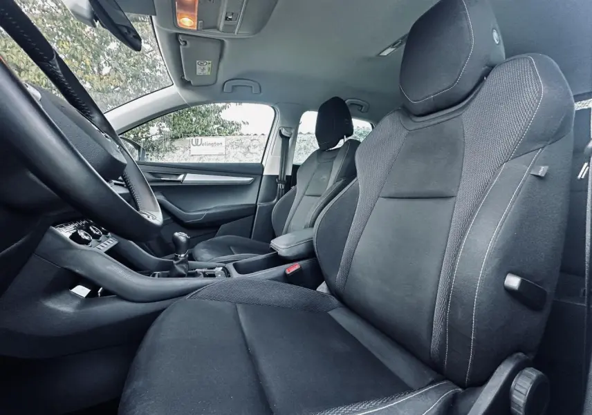 Vue intérieure côté droit du Skoda Karoq 2024, sièges avant noirs avec coutures blanches et levier de vitesse manuel.
