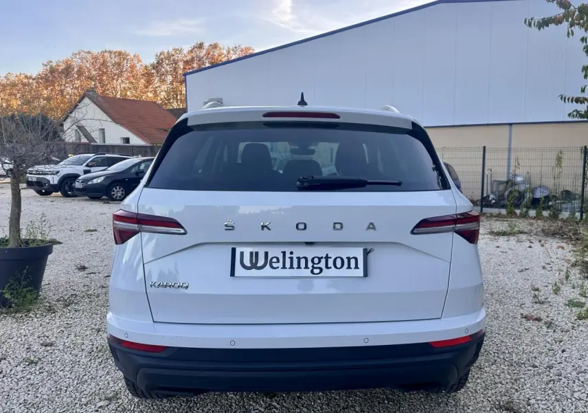 Vue arrière d'un Skoda Karoq blanc 2024 avec feux arrière LED et logo ŠKODA bien visible.
