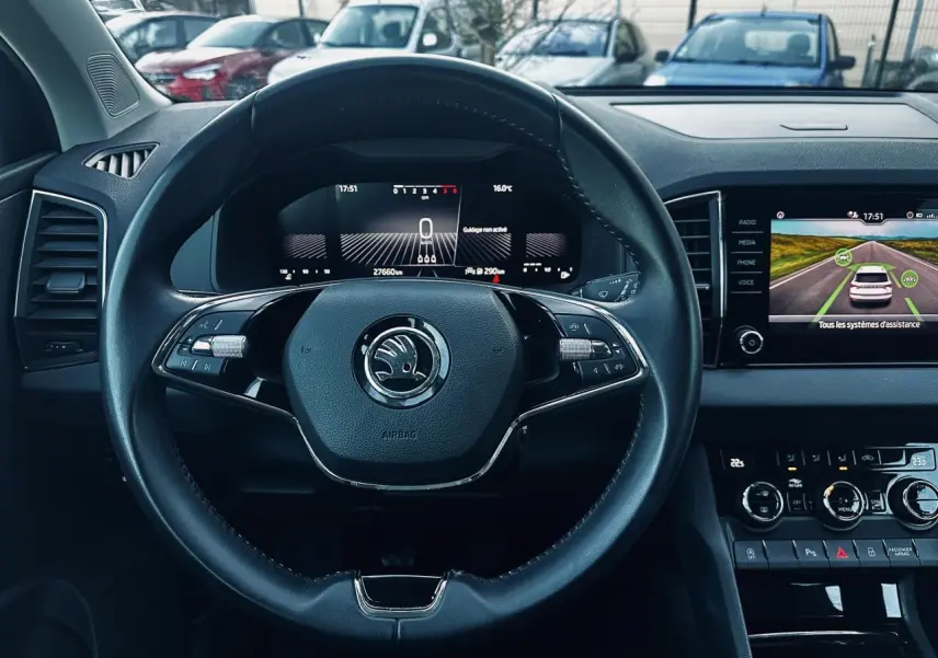 Vue intérieure centrée sur le volant noir du Skoda Karoq 2024 avec tableau de bord digital et écran tactile.