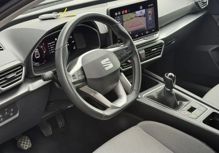 Vue intérieure côté conducteur du SEAT Leon 2.0 TDI noir Minuit, volant cuir multifonction et écran tactile avec caméra de recul.