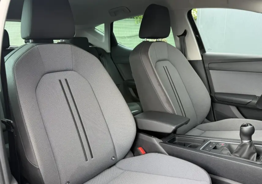 Vue intérieure côté droit des sièges avant gris clair de la SEAT LEON 2025 avec boîte manuelle et accoudoir central noir.