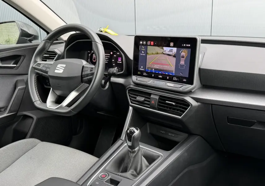 Intérieur avant droit du SEAT Leon noir Minuit, volant cuir multifonction et écran tactile avec caméra de recul affichée.