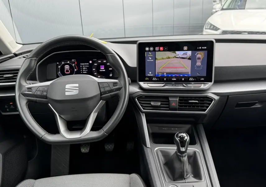 Vue intérieure du tableau de bord et volant cuir multifonction d'une SEAT LEON 2.0 TDI 115 Style avec écran tactile et caméra de recul.