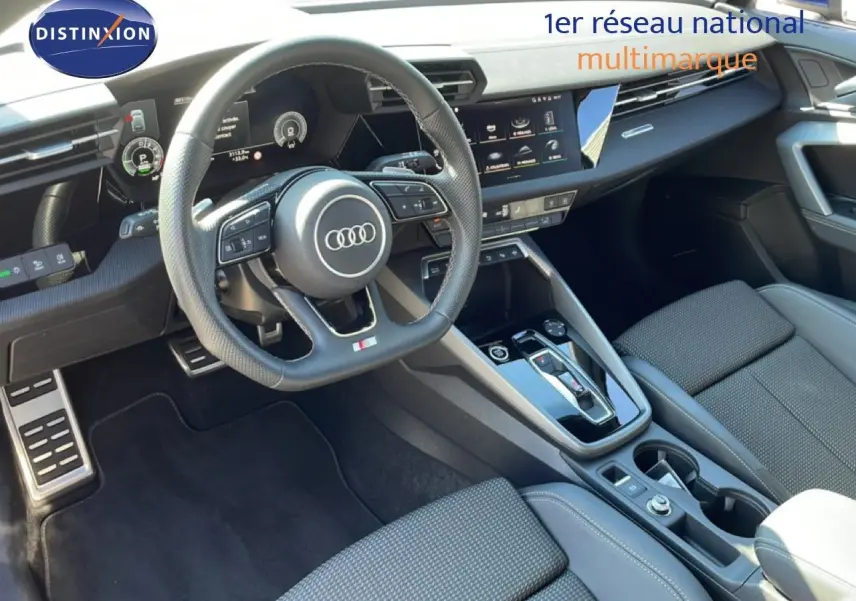 Vue intérieure de l'Audi A3 Sportback 2025, tableau de bord et volant multifonction en cuir noir, console centrale moderne.