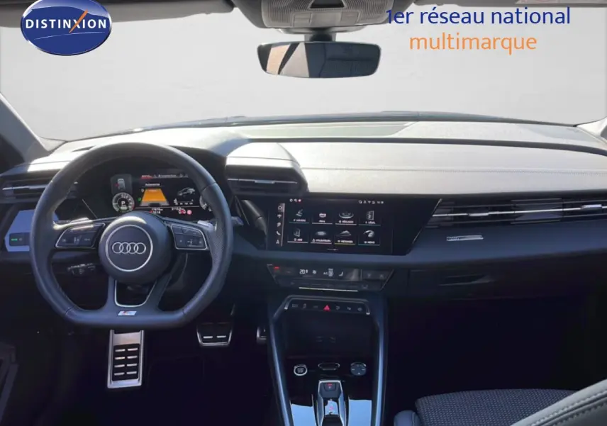 Vue intérieure avant de l'Audi A3 Sportback 2025, tableau de bord noir avec écran tactile et volant multifonction.