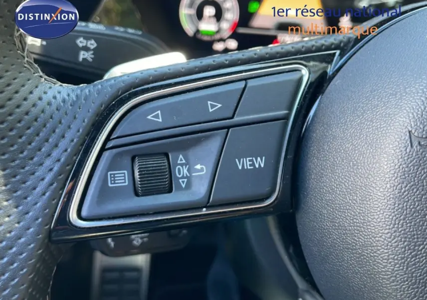 Gros plan sur les commandes gauche du volant en cuir perforé de l'Audi A3 Sportback 2025, avec affichage numérique en arrière-plan.