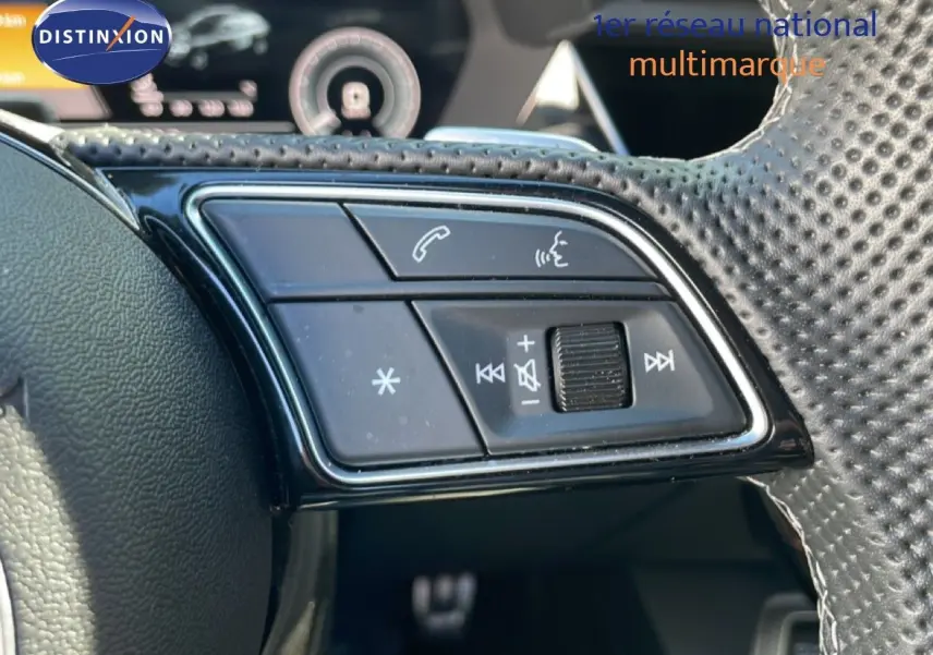 Gros plan sur les commandes de volume et téléphone au volant perforé de l'Audi A3 Sportback bleu Navarre 2025.
