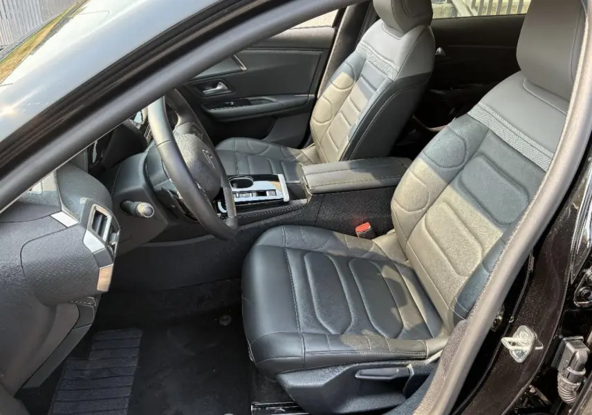 Vue intérieure côté conducteur de la Citroën C5 X 2024 noir perla, mettant en valeur les sièges cuir et la console centrale moderne.