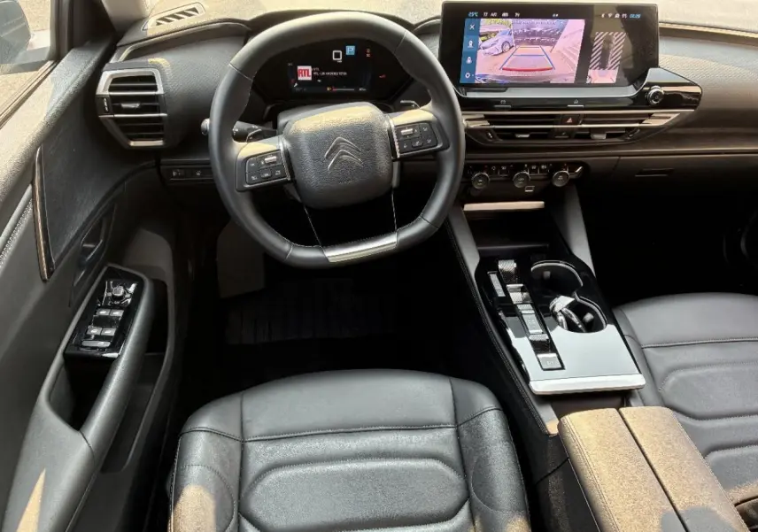 Intérieur noir du Citroën C5 X 2024, vue du poste de conduite avec volant multifonction et écran tactile central.